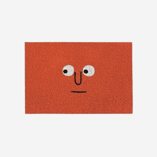 Röd dörrmatta med roligt ansikte