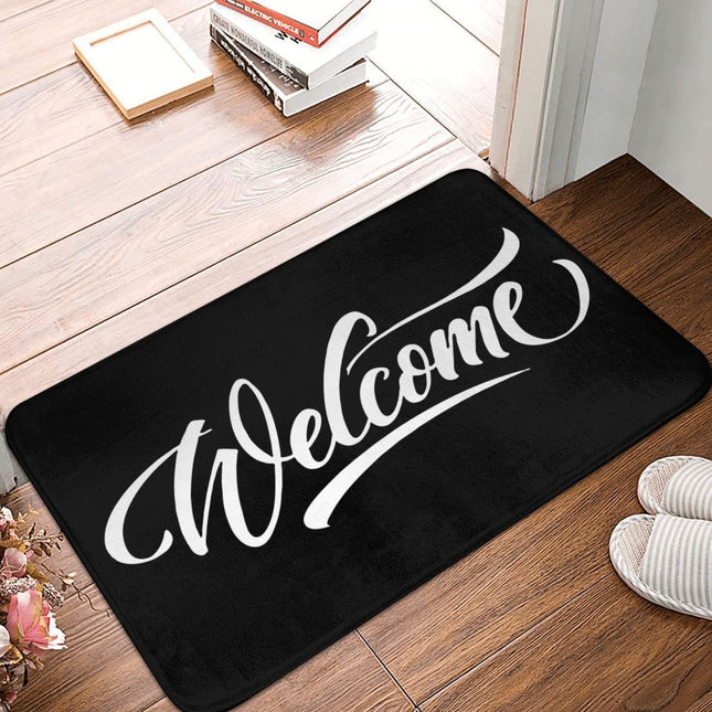 Svart dörrmatta med 'Welcome' i skrivstil