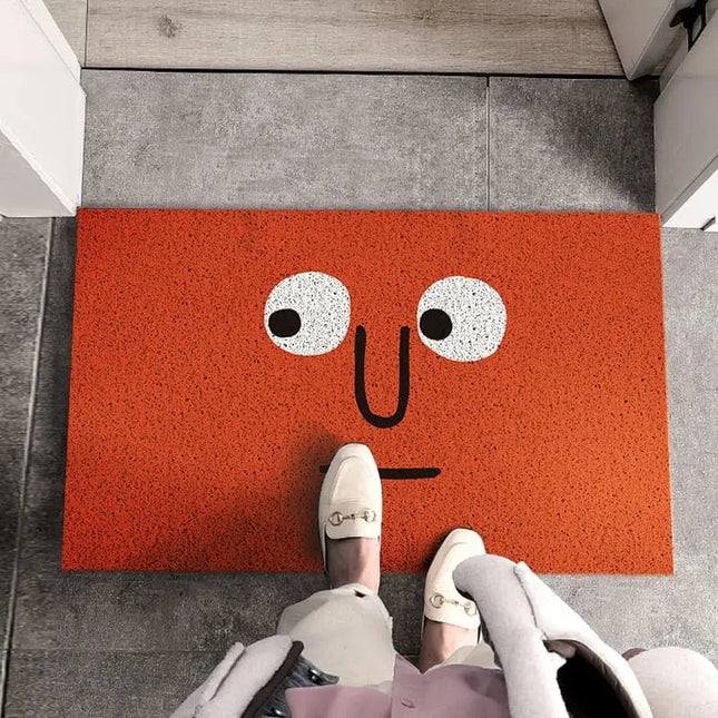 Röd dörrmatta med roligt ansikte